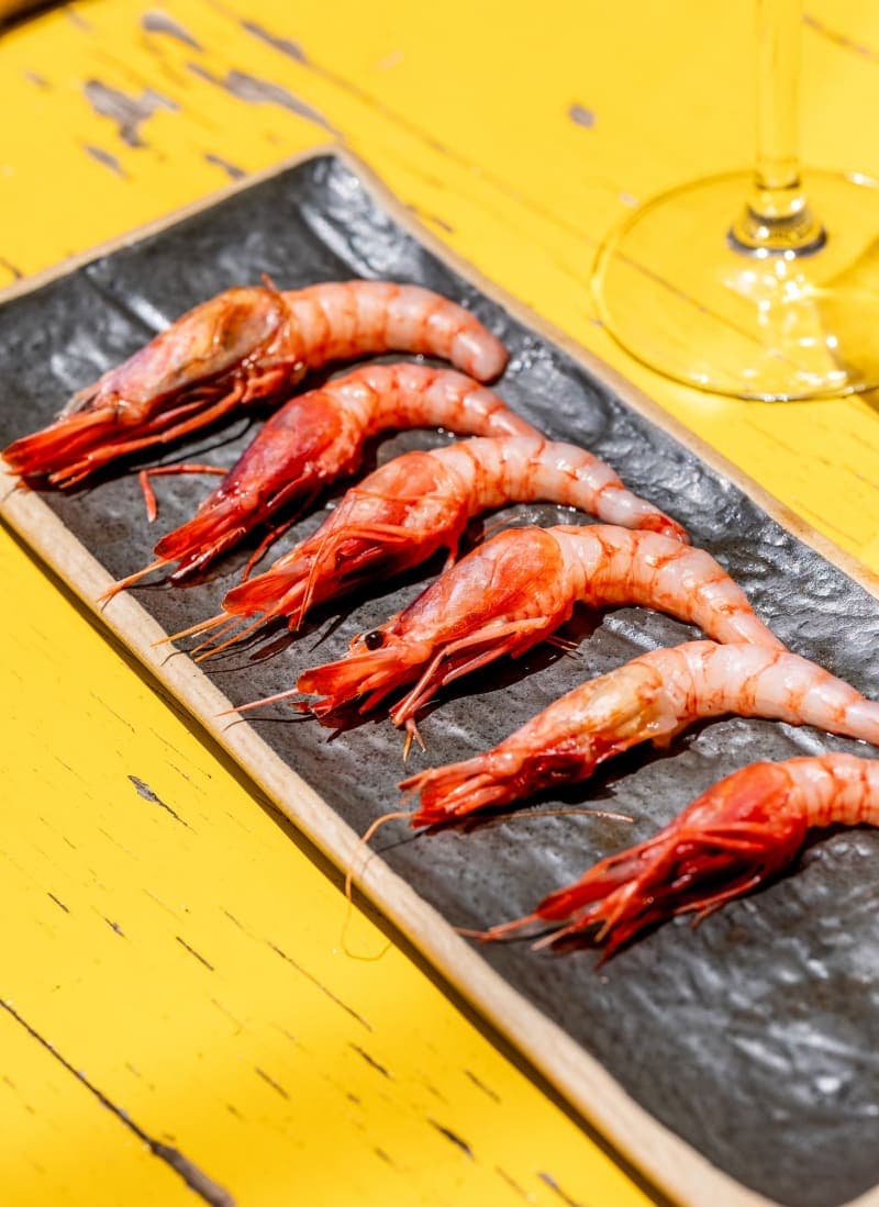 Six cooked prawns served on a plate.